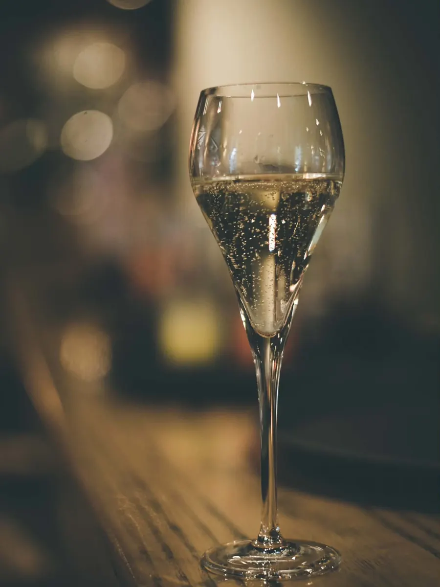Een fluitglas met bubbels op de houten toog.