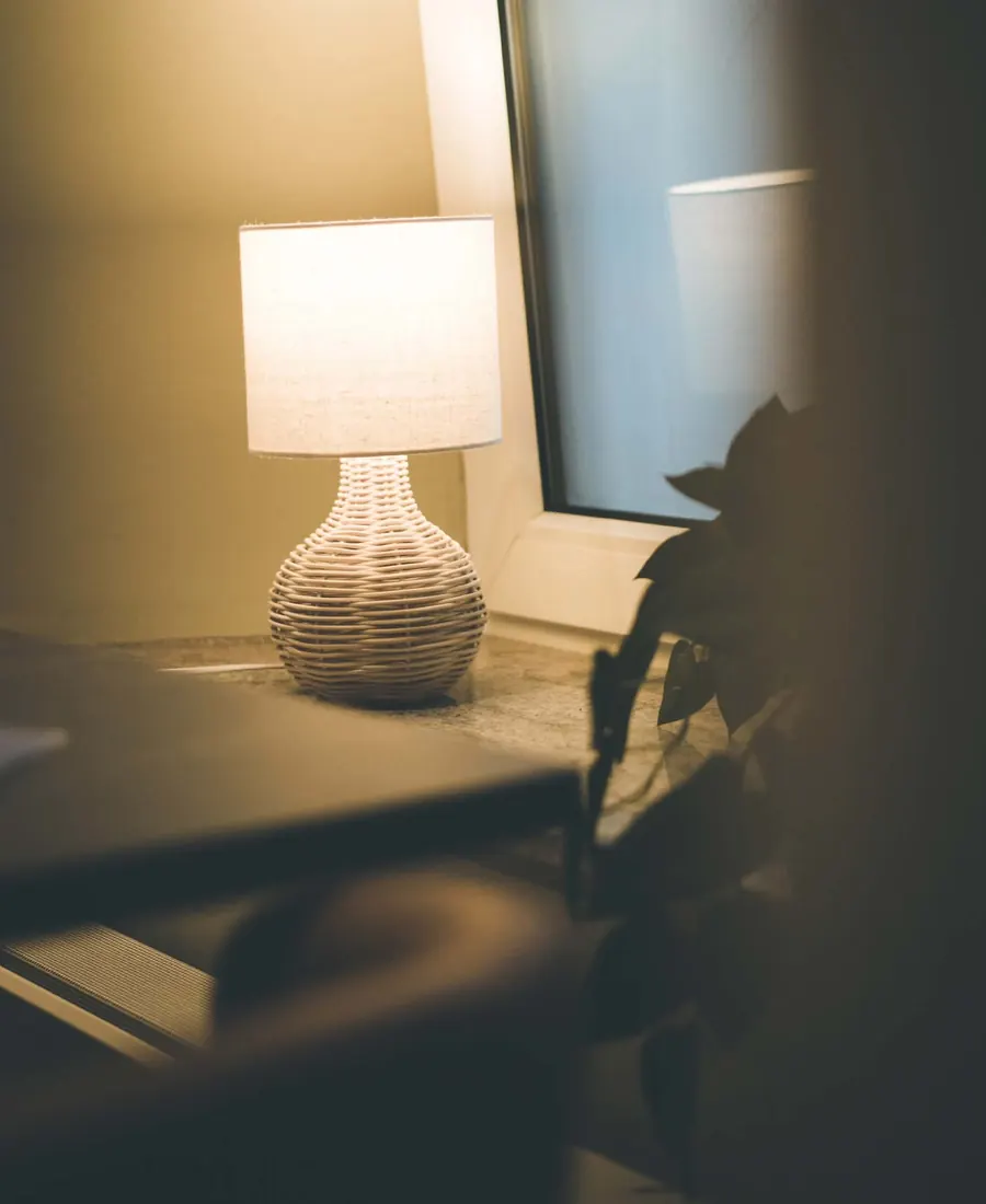 Une lampe en céramique allumée près d’une fenêtre.