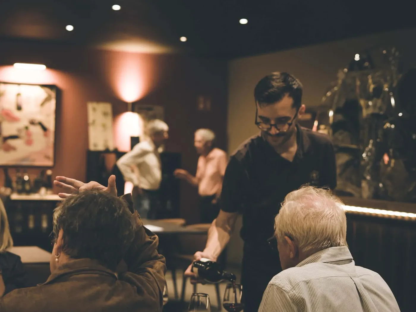 Un serveur verse du vin à une table de clients.