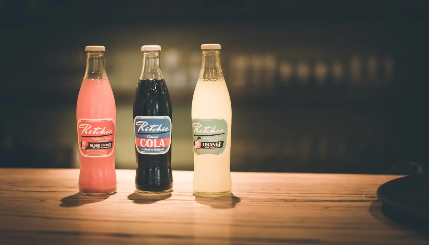 Trois bouteilles de sodas belges Ritchie sur le comptoir.